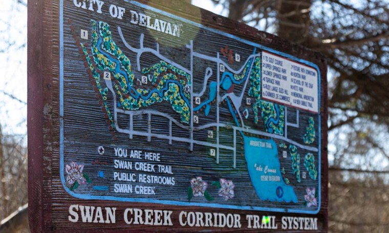 A wooden sign of the Swan Creek Corridor Trail System in Delavan